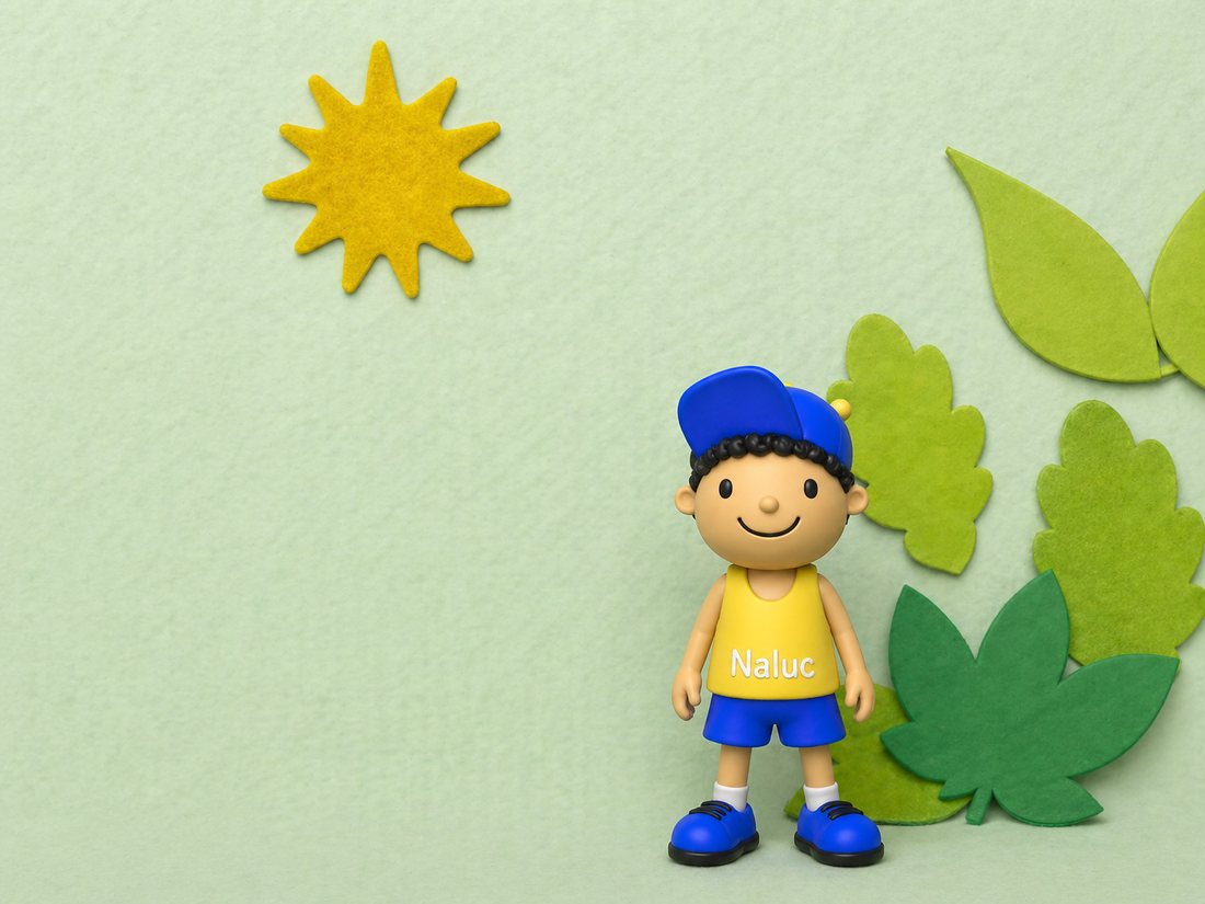 Naluc sonriente junto a hojas de fieltro de distintos verdes y un sol amarillo.